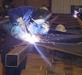 A welder at J.B. Steel working on welding a beam.